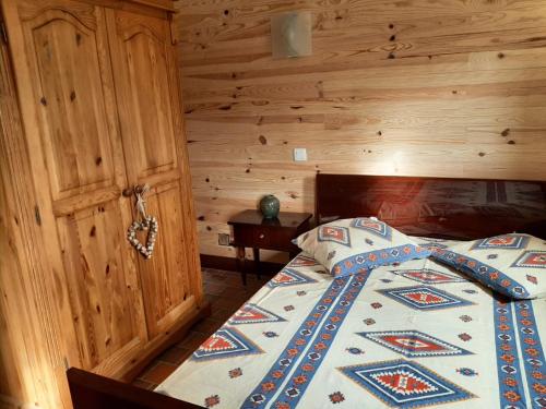 1 dormitorio con 1 cama con pared de madera en La Caverne du Buisson, en Truffe