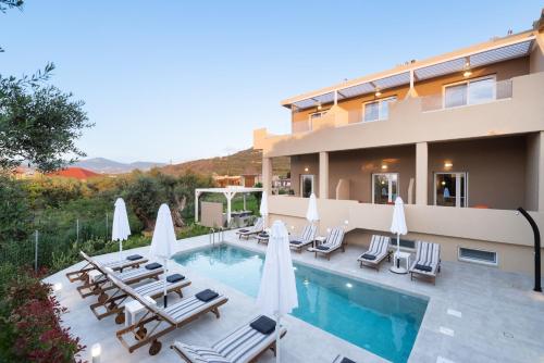 Villa con piscina con sillas y sombrillas. en Meliora Suites en Dhrapaniás