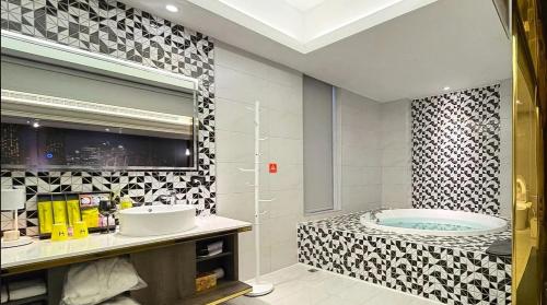 a bathroom with a tub and a sink at H Motel璽悅國際精品旅館 in Zhubei