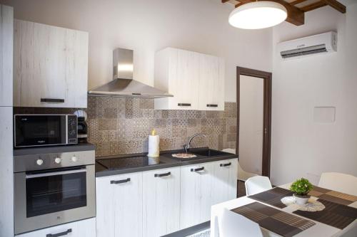 a kitchen with white cabinets and a microwave and a table at casa vacanza zu ciano in Marausa