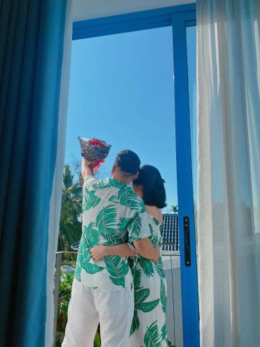 a man and a woman are standing outside a window at SANTORI Hoi An Homestay in Hoi An