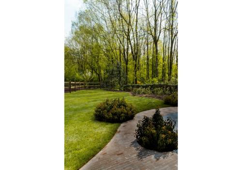 a garden with trees and a brick walkway at Vakantiehoeve 'De Zandrug' in Stekene
