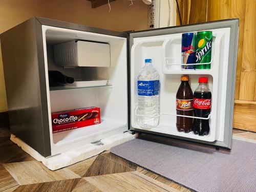 an open refrigerator with bottles of water and soda at Turtle Wood Cabin in Tangalle