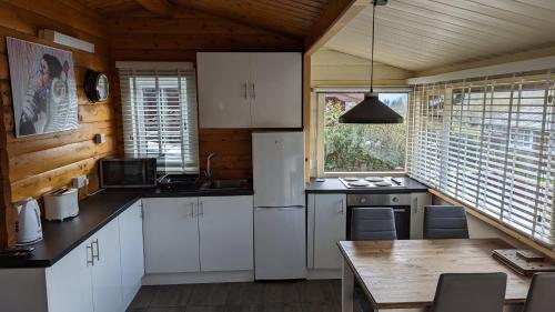 a kitchen with white cabinets and a wooden ceiling at Snowdonia Log cabin in Trawsfynydd