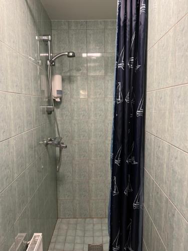 a shower with a black shower curtain in a bathroom at Gästhem Neptun in Mariehamn