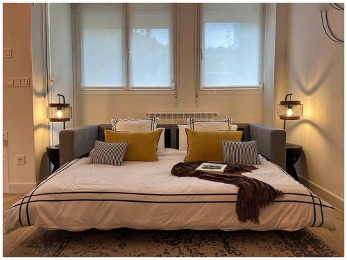 uma cama grande num quarto com duas janelas em Elegance Lifestyle - Parking Gratuito! em San Sebastián