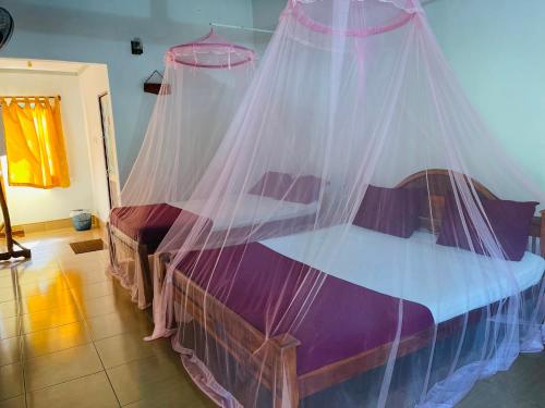 a bedroom with a bed with a mosquito net at New Roy Guest House in Kalkudah