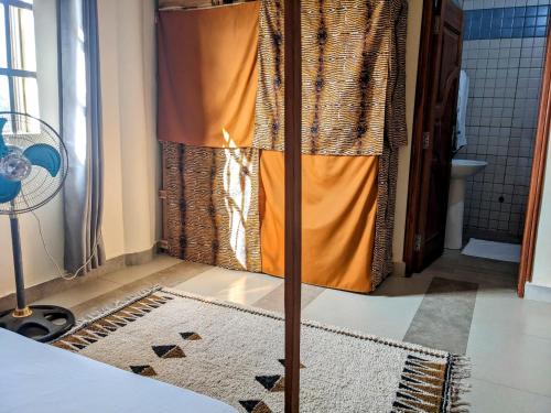 y baño con cortina de ducha naranja y alfombra. en Porto-Novo logement lumineux et calme, en Porto Novo