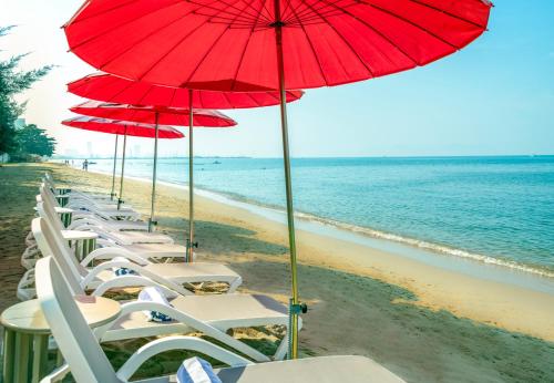 a row of chairs and umbrellas on a beach at Bayphere Hotel Pattaya JC in Na Jomtien