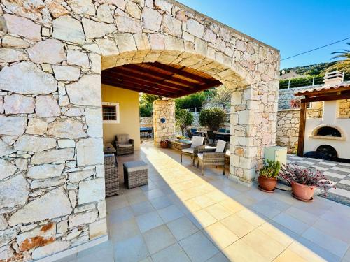 an outdoor patio with a stone wall and an archway at Kiki's Seaview Villa in Gerani