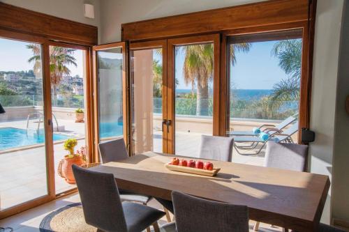 a dining room with a table and views of the ocean at Kiki's Seaview Villa in Gerani