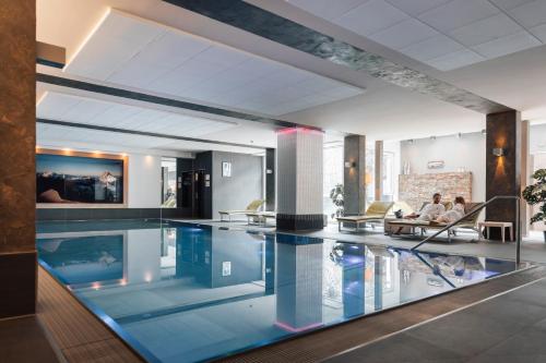 a large swimming pool with people sitting on chairs in a building at Hotel Fliana Ischgl in Ischgl