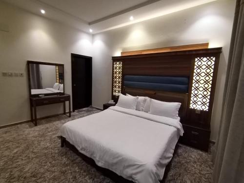 um quarto com uma grande cama branca e um espelho em امارلس للشقق الفندقية em Khamis Mushayt