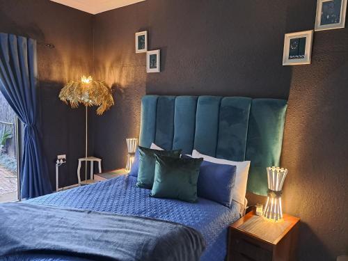 a bedroom with a blue bed with a blue headboard at Pandora's Guest Lodge in Klerksdorp