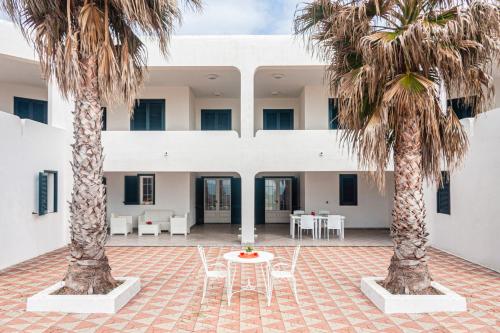 a courtyard with two palm trees and a table and chairs at Appartamenti Frontemare in Marina di Mancaversa