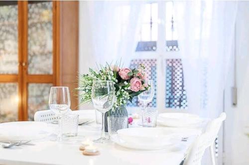 a white table with glasses and a vase of flowers at Los Duendes in Almería