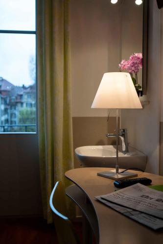 a desk with a lamp on a table with a sink at Hotel Marthahaus in Bern