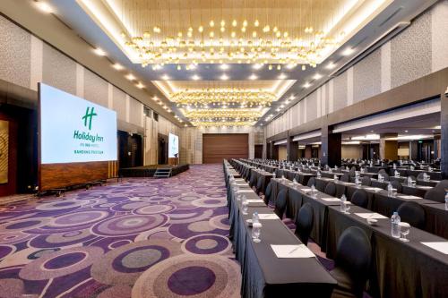 a large banquet hall with tables and a screen at Holiday Inn Bandung Pasteur by IHG in Bandung
