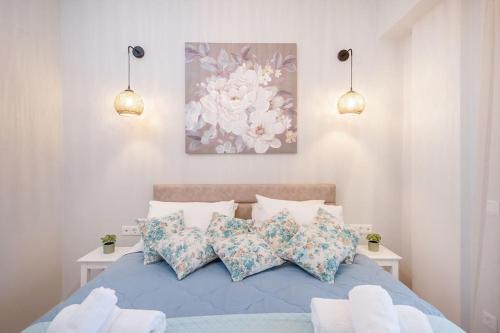 a bedroom with a blue bed with pillows and a painting at Frises Corfu Town Apartment in Ágios Rókkos