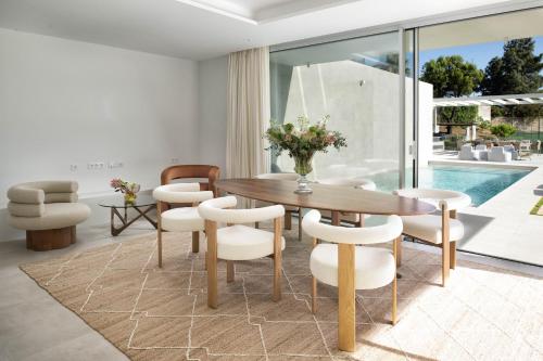 a dining room with a wooden table and white chairs at Villa Alma in Marbella