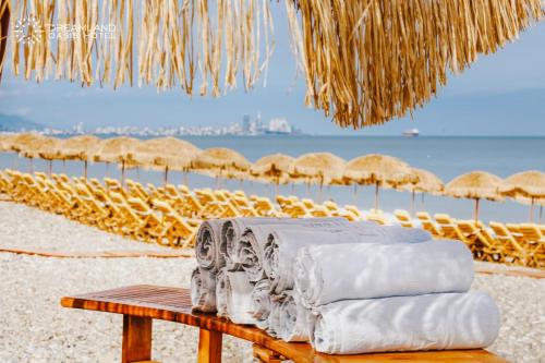 a table with towels on a beach with straw umbrellas at Dreamland Oasis in Chakvi