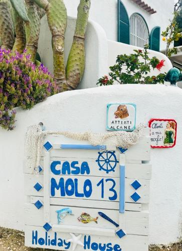 a sign for a mola mola house with flowers at Casa Molo 13 in Mattinata