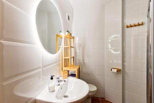 een witte badkamer met een wastafel en een spiegel bij Casa Acacia in Nerja