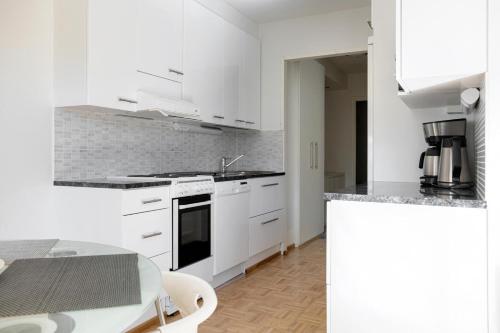 a white kitchen with white cabinets and a table at Apartments Karviaismäki in Helsinki