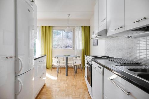 a kitchen with white appliances and a table in it at Apartments Karviaismäki in Helsinki