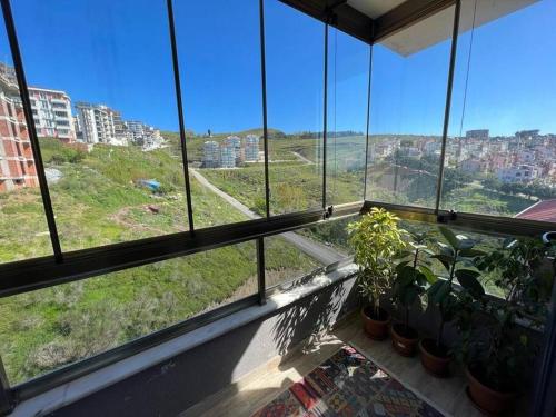 a room with windows with plants and a view of a city at Yeni Dairede Manzaralı Lüks Mobilyalı Ferah Daire in Sinop