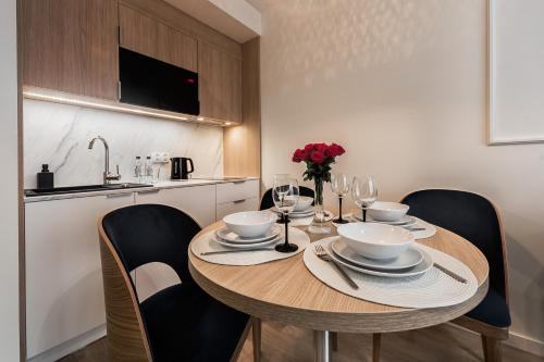 a dining room table with chairs and a kitchen at Aurum Aparthotel - Nowe Apartamenty blisko Plaży - Neue Appartements in Strandnähe in Świnoujście