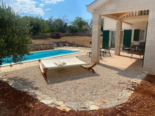 a swimming pool with a bench next to a house at Hvaretta Villas in Stari Grad