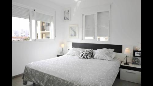 a white bedroom with a bed with pillows and windows at FREDOV in Benalmádena