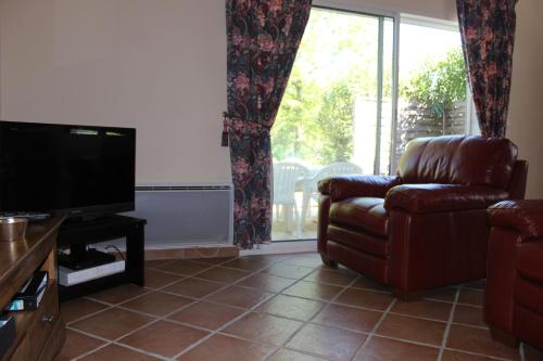 a living room with a couch and a television at Les Pics Blancs in La Courtète