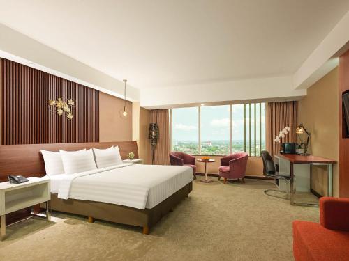 ジョグジャカルタにあるジ アラナ ジョグジャカルタ ホテル アンド コンベンションセンターのベッドとデスクが備わるホテルルームです。