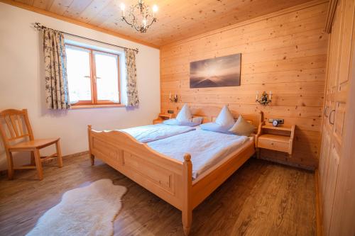 um quarto com uma cama, uma cadeira e uma janela em Ferienwohnung Berghof em Wallgau