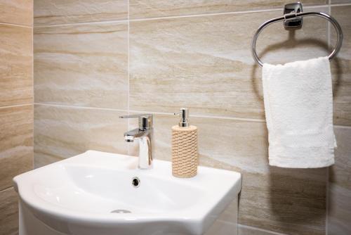 baño con lavabo blanco y toalla en Pensiunea Abrudan, en Scrind-Frăsinet