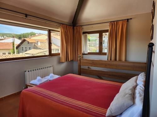 a bedroom with a red bed and a large window at El Torreón I in Hoyos del Espino