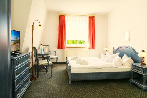 a bedroom with a bed and a desk and a window at Hotel Esplanade Garni in Kühlungsborn