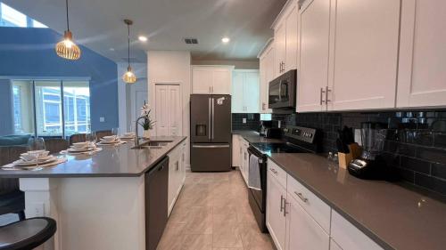 uma grande cozinha com armários brancos e electrodomésticos pretos em Beautiful 5bed home close to Disney 1131KING em Kissimmee