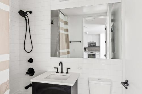 La salle de bains blanche est pourvue d'un lavabo et d'une douche. dans l'établissement E Village 1BR w WD Elevator Gym NYC-889, à New York