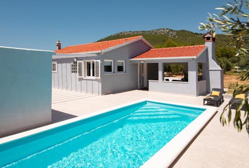 une villa avec une piscine en face d'une maison dans l'établissement House Potirna, à Blato