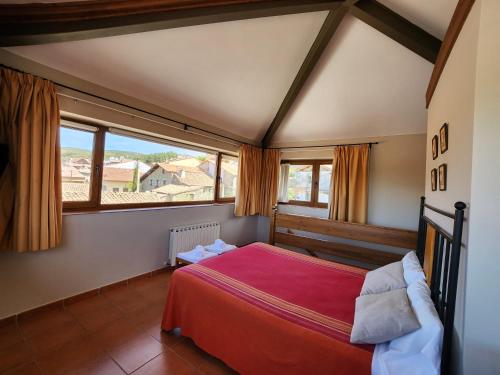 Schlafzimmer mit einem roten Bett und einem großen Fenster in der Unterkunft El Torreón I in Hoyos del Espino