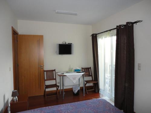 a bedroom with a table and a tv on the wall at Lena's Home in Ponta Delgada