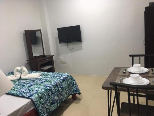 Cette chambre comprend un lit, une table et une télévision. dans l'établissement Donadel Hometel, à Iloilo