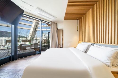 a bedroom with a large white bed and a balcony at Gwanganli The Club Hotel in Busan