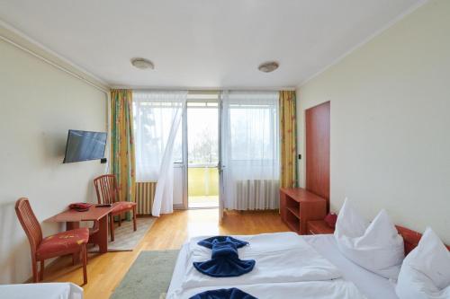 Retro Lido - Vonyarcvashegy في فونيارتسفاشغي: غرفة فندقية بسرير وطاولة وكراسي