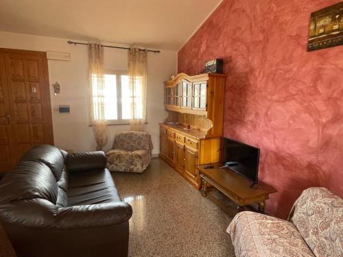 Una sala de estar con un sofá de cuero y un televisor. en Dimora Pina sul mare, en Codaruina