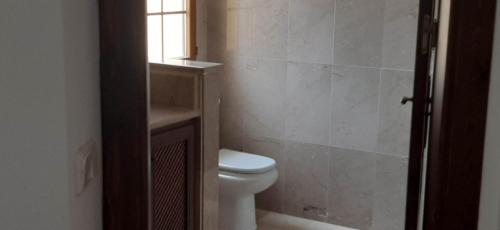 a bathroom with a toilet and a window at La Manga Club Townhouse in Cartagena