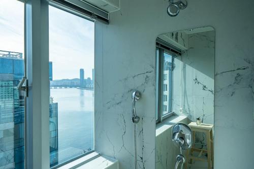 a bathroom with a shower and a window with a view at Gwanganli The Club Hotel in Busan